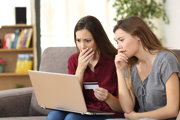 Parent looking shocked while reading a laptop screen.