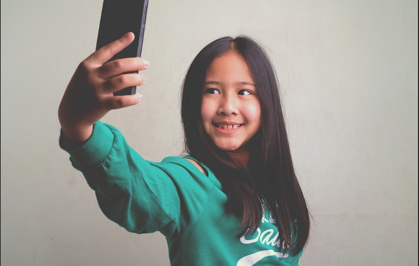 Teenage girl holding up her mobile phone taking a selfie.