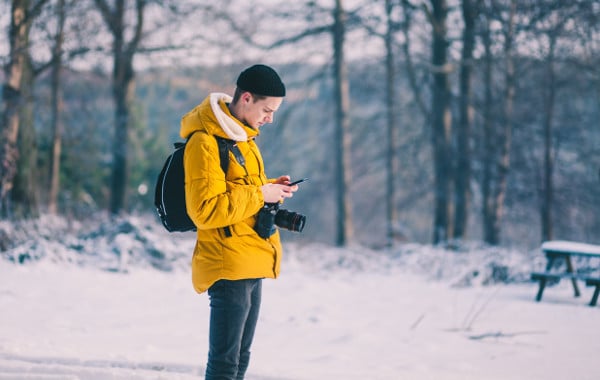 Teenager standing outside using his mobile phone.
