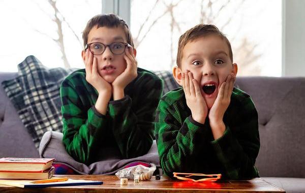 Tow kids with their hands on their cheeks appearing surprised.