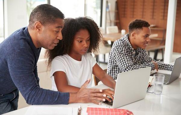 Father helping his daughter on a laptop computer.