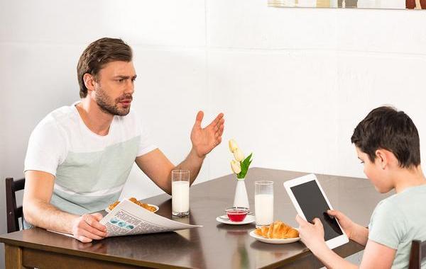 Father trying to talk with his son at the breakfast table.