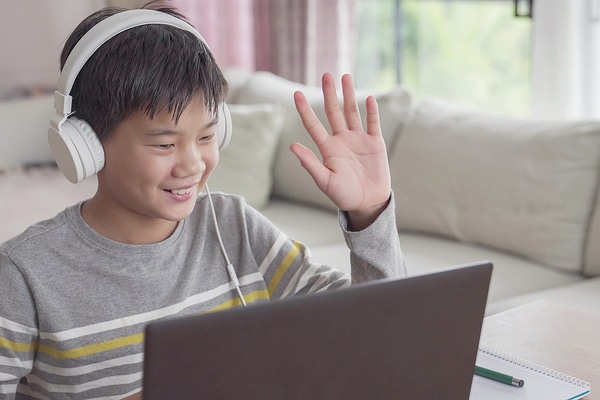 Young teen wearing headphones sitting in front of of a laptop computer.