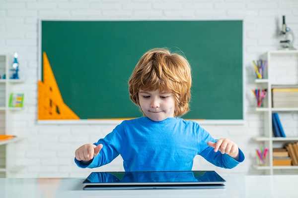 Child sitting at a table using a computer.