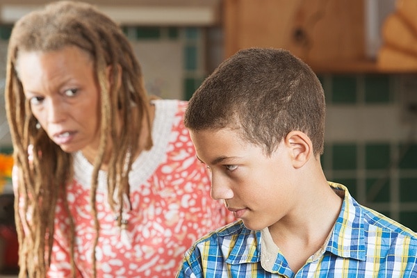 Mother looking concerned while her son hides his phone.